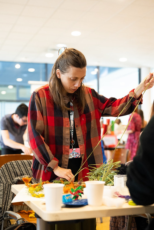 une personne coud des fils de papier pour confectionner l'adaptation de l'affiche 