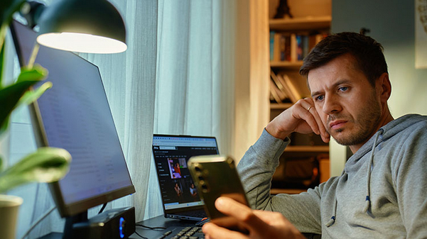 Homme devant ordinateur avec portable dans la mai